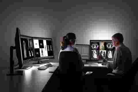 A radiologist showing diagnostic images to a colleague using Barco Coronis Fusion 6MP displays