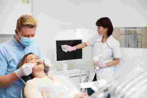 dental practice with dentist, patient and assistant cleaning a white Nio dental display