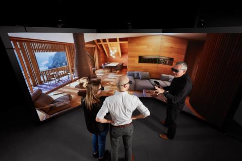 An architect and a young couple stand in front of Barco Canvas screen looking at interior of modern house. 