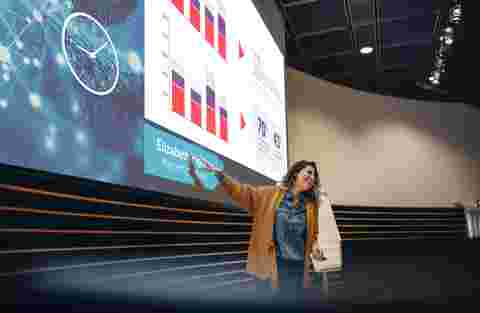 Businesswoman gesturing at projection screen and making a presentation during seminar. Female speaker giving presentation in conference.