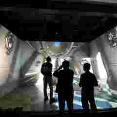 Three persons stand in the Barco CAVE with RigiFlex screens at the Shenzen SUST VR Center