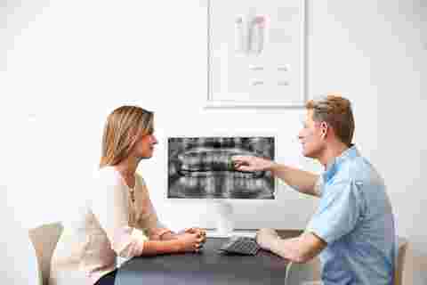 dental practice consultation room with dentist and patient discussing x-ray image