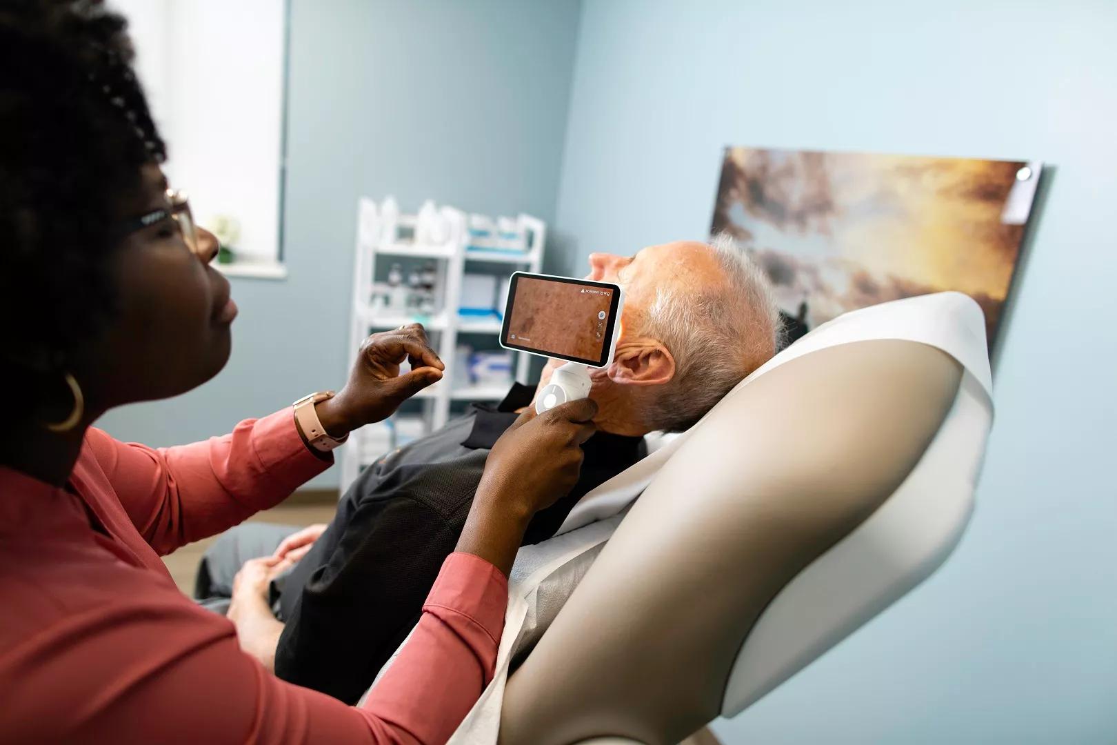 A dermatologist using the Demetra Scope to view a lesion on a patient's cheek
