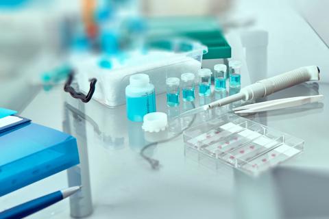 Blurred background for histopathology-related presentation. Stained histological tissue samples on glass, fixed tissue, automatic pipette and other work-related tools. Toned image, text space. 