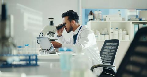 Scientist, sample and man with microscope in lab for clinical trial, virus study and experiment. Science, innovation and employee with equipment for medical research, vaccine development and analysis.