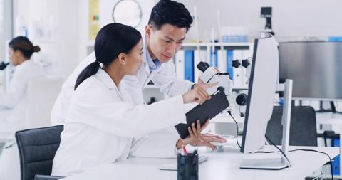 Computer, scientist and discussion with tablet in lab, research biotech innovation or medical development. Healthcare advancement, trial results and people check pharma test, tech and medicine report.