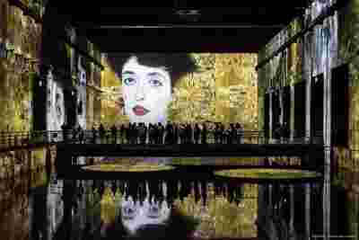 Visitors at immersive Klimt exhibition at Bassins de Lumières, Bordeaux, France, a Culturespaces artainment space powered Barco projection mapping. 