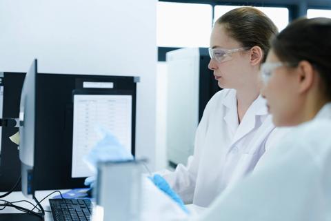 Team of female scientists analyzing digital pathology slides on computer. Caucasian and Asian researchers reviewing histology data for medical diagnosis in modern lab.