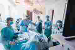 Process of gynecological surgery operation using laparoscopic equipment. Group of surgeons in operating room with surgery equipment. Background