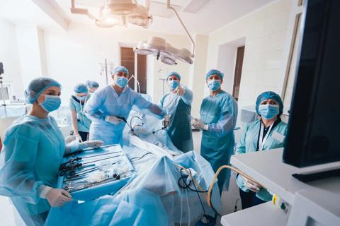 Process of gynecological surgery operation using laparoscopic equipment. Group of surgeons in operating room with surgery equipment. Background