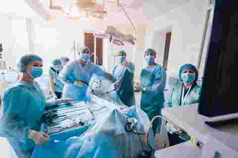 Process of gynecological surgery operation using laparoscopic equipment. Group of surgeons in operating room with surgery equipment. Background