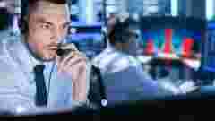 In Monitoring Room Technical Support Specialist Speaks into Headset. His Colleagues are Working in the Background. military & government