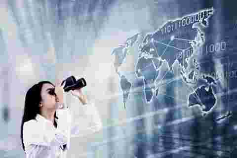 Double exposure of young businesswoman using binoculars to looking at world map with connection network on the virtual screen background