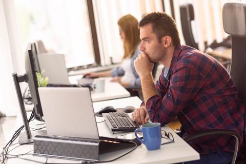 Two business colleagues sitting at their desks in an office, working; software developers coding