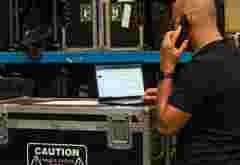 A person accessing the Projector Management Suite tool while standing in a rental warehouse