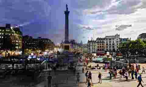 Two photographs of Trafalgar Square merged together to show the transition from night to day in a single image.