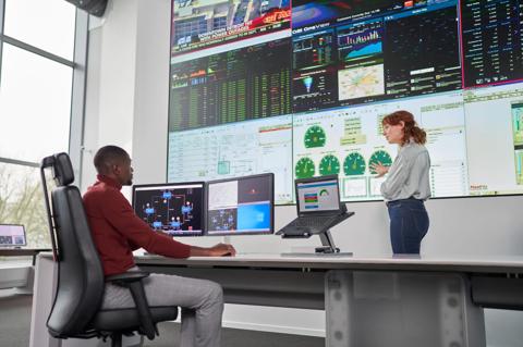 Two people in enterprise pod watching the large video wall, operator and control room manager